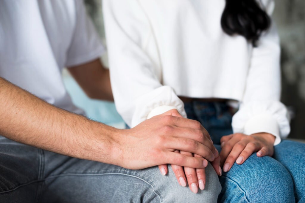 Hombre joven y mujer sentados juntos y tomados de la mano